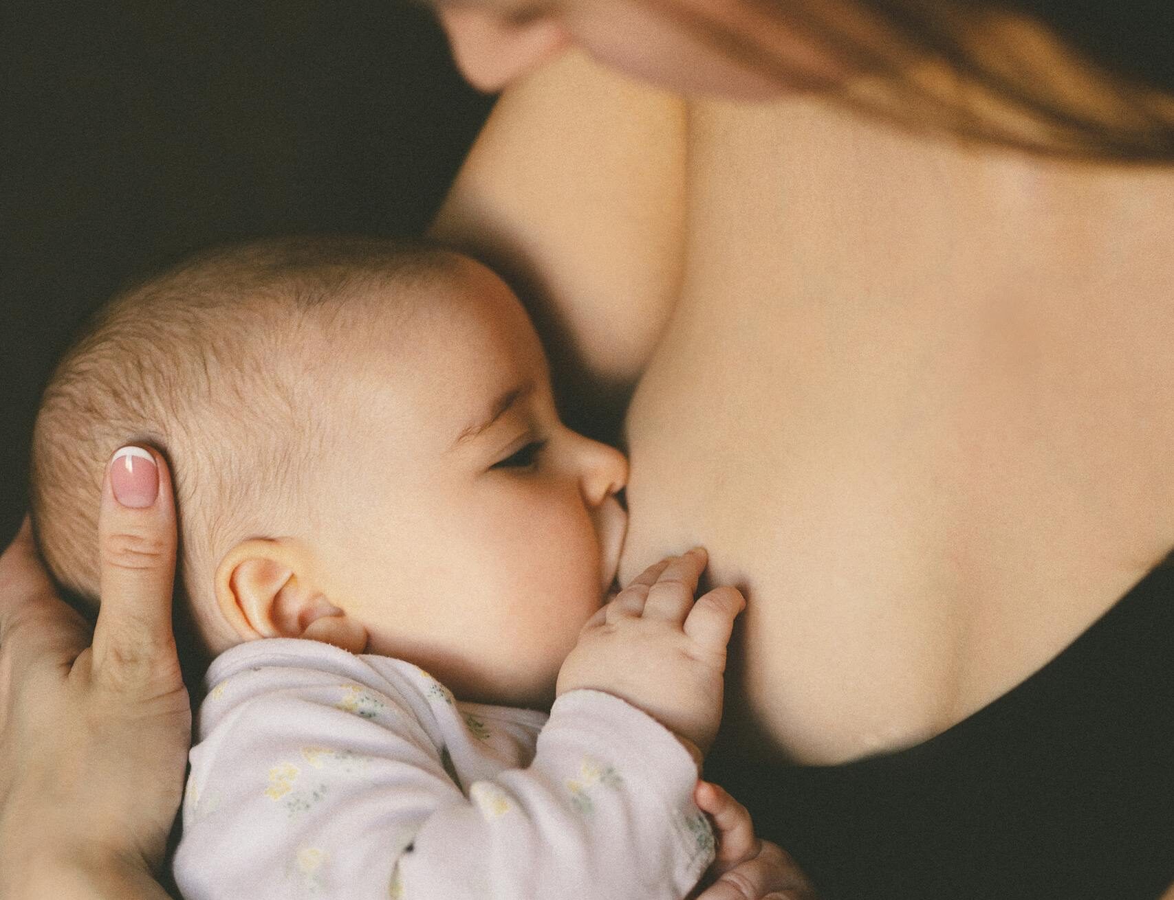 A close-up of a mother lovingly breastfeeding her baby, symbolizing care and motherhood.