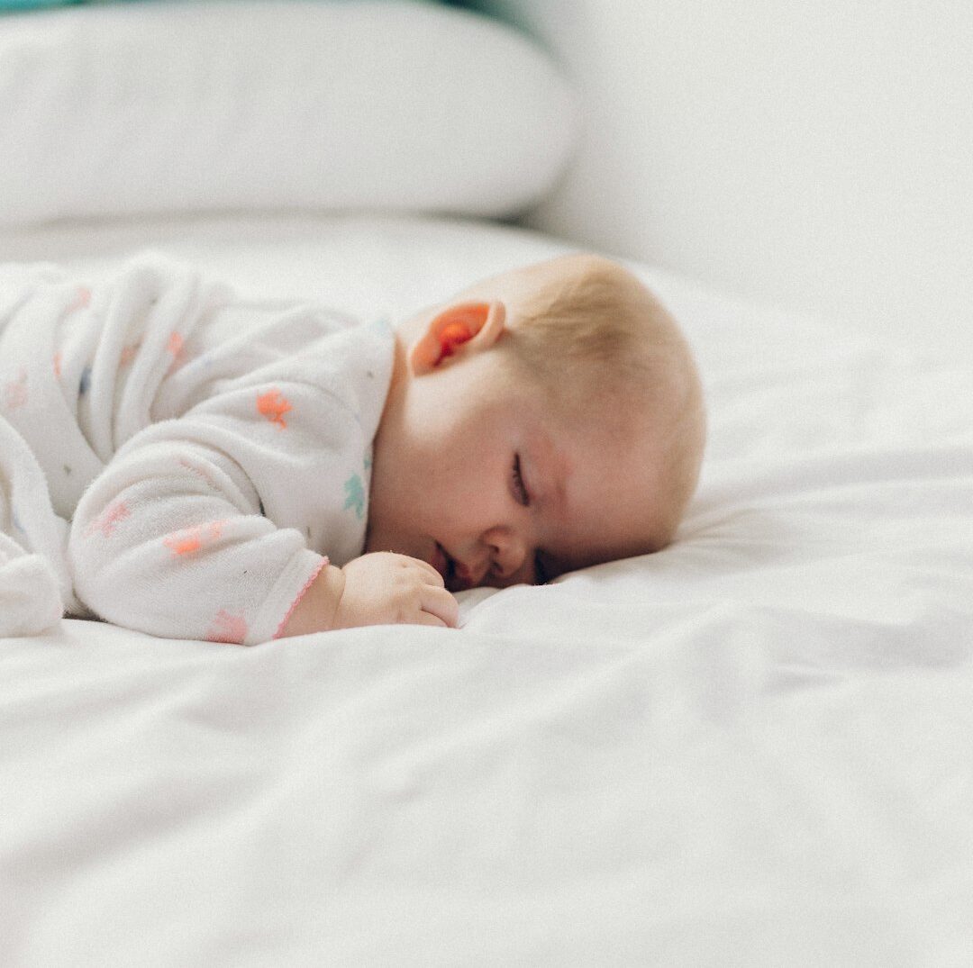 photo of baby laying on bed